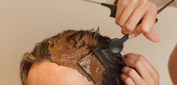 aplicando un producto de barro en el pelo a una chica con un pincel